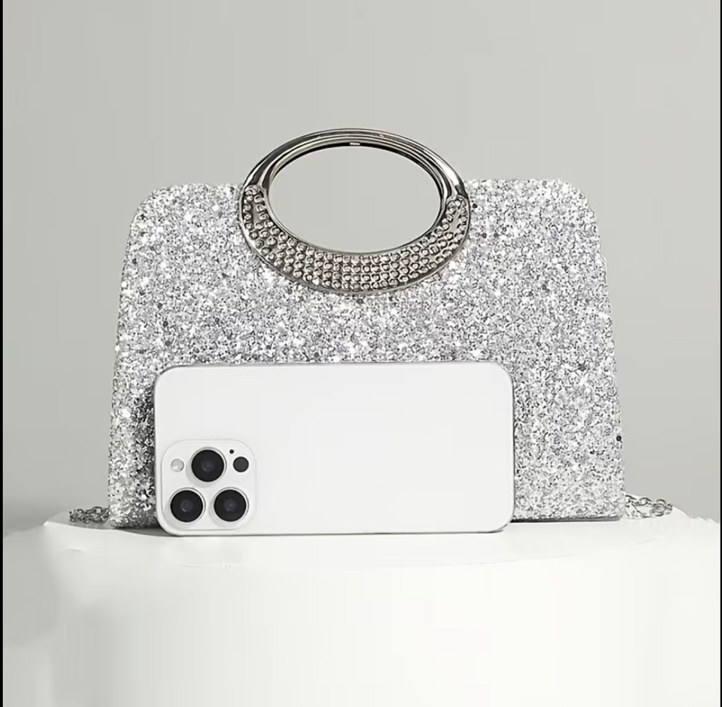 Silver evening bag shown next to a phone