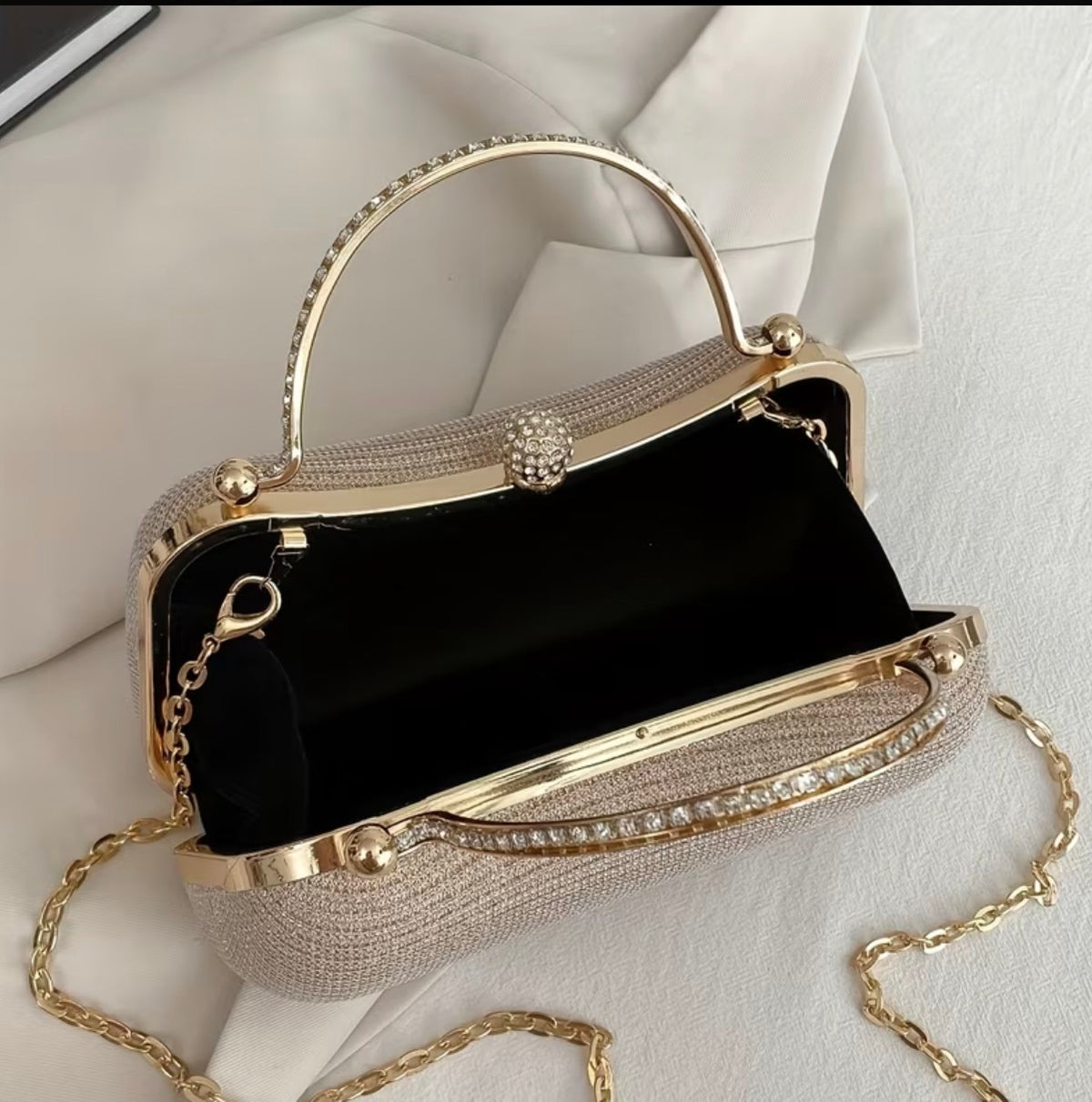 Gold-tone framed clutch bag open to show interior